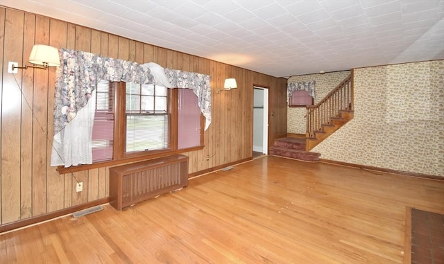 81 Osborne Ter, Springfield, MA 01104 - unfurnished living room featuring radiator heating unit, wood finished floors, stairs, and wood walls