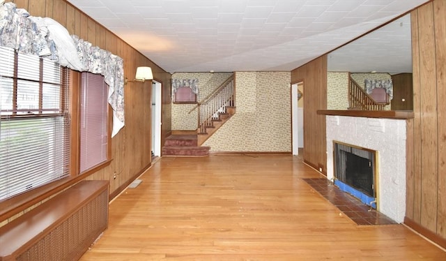 81 Osborne Ter, Springfield, MA 01104 - unfurnished living room with radiator heating unit, wood finished floors, wooden walls, stairs, and a fireplace