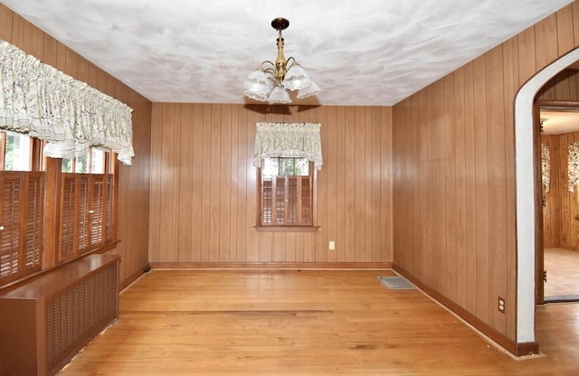 81 Osborne Ter, Springfield, MA 01104 - unfurnished dining area featuring radiator heating unit, arched walkways, healthy amount of natural light, and wooden walls