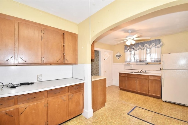 81 Osborne Ter, Springfield, MA 01104 - kitchen featuring freestanding refrigerator, arched walkways, ceiling fan, brown cabinets, and light flooring