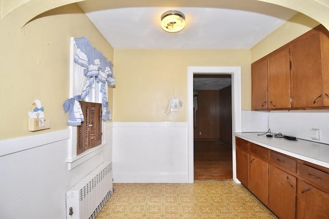 81 Osborne Ter, Springfield, MA 01104 - kitchen with radiator, light floors, light countertops, wainscoting, and arched walkways