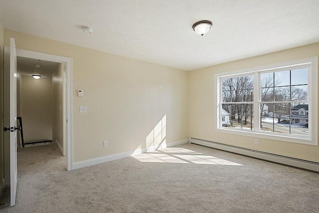 carpeted empty room featuring baseboard heating, a smoke detector, and baseboards
