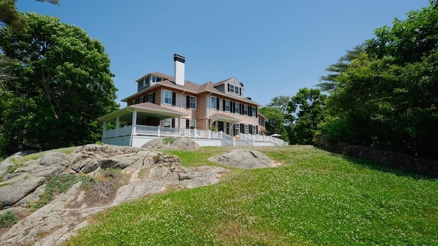 rear view of house with a porch and a lawn