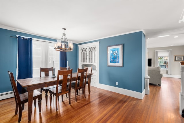 dining space with wood-type flooring, crown molding, and a notable chandelier