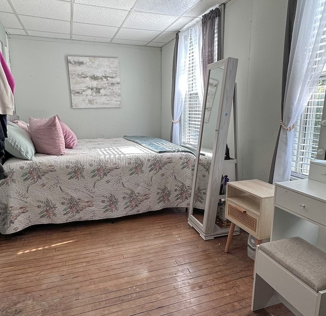 bedroom with a paneled ceiling and wood-type flooring