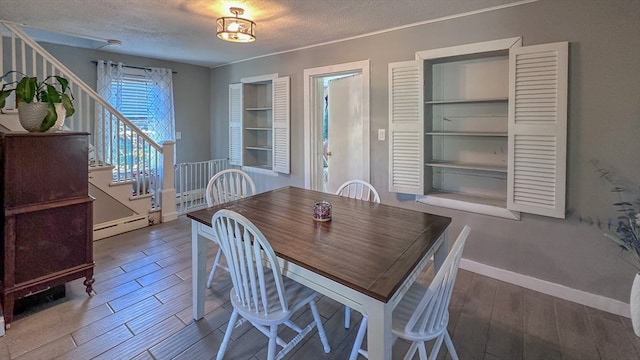 dining area featuring a textured ceiling, a baseboard heating unit, and wood-type flooring