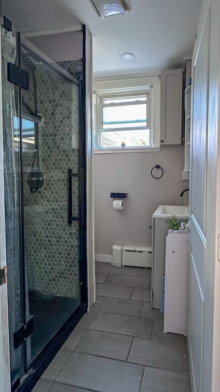 bathroom featuring a shower with door, a baseboard heating unit, and sink