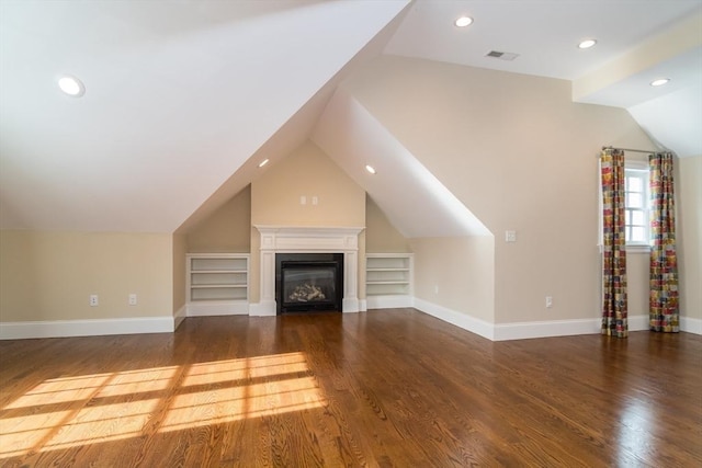 unfurnished living room featuring vaulted ceiling, dark hardwood / wood-style floors, and built in shelves