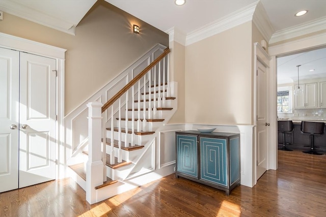 staircase with hardwood / wood-style flooring and crown molding