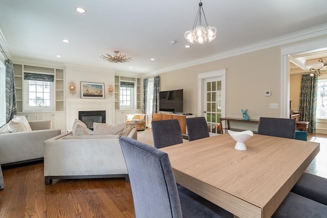 dining space with ornamental molding, a notable chandelier, dark hardwood / wood-style flooring, and built in shelves