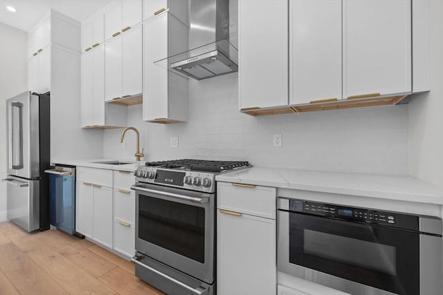1 Marion St Unit 2, Cambridge, MA 02141 - kitchen with stainless steel appliances, wall chimney range hood, light wood-type flooring, white cabinets, and a sink