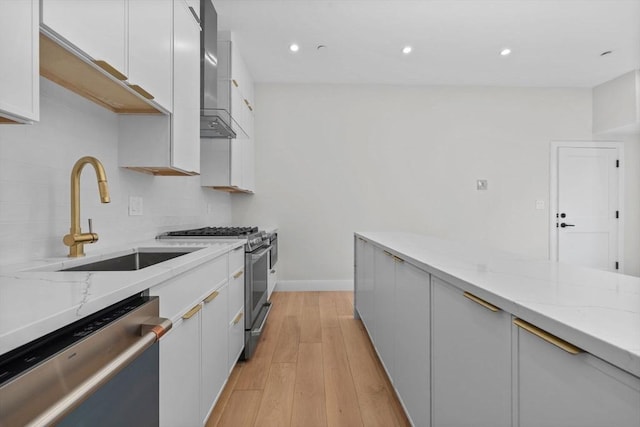 1 Marion St Unit 2, Cambridge, MA 02141 - kitchen with appliances with stainless steel finishes, a sink, light stone counters, white cabinets, and light wood-style flooring
