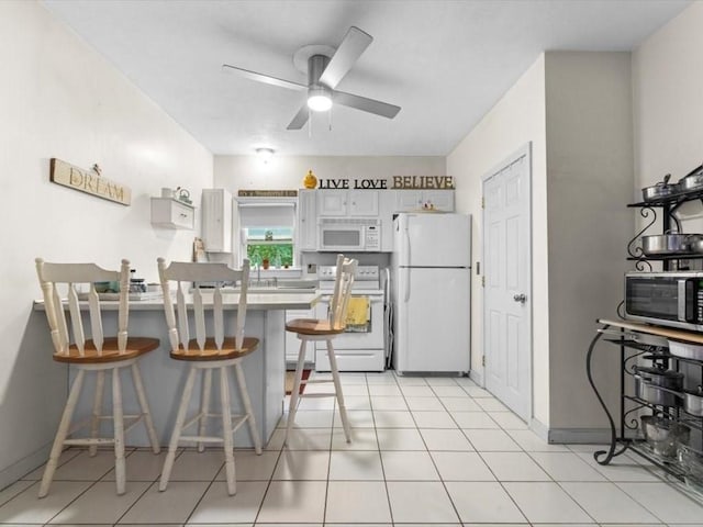 135 Border St Unit 135, Northbridge, MA 01588 - kitchen with white appliances, a ceiling fan, a peninsula, a kitchen breakfast bar, and white cabinets