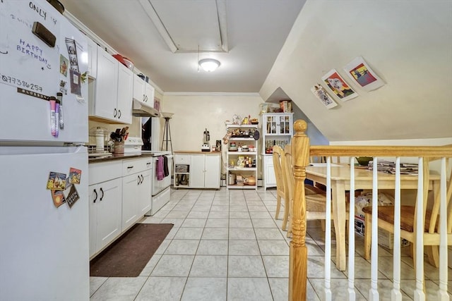 kitchen featuring white cabinetry, vaulted ceiling, light tile patterned floors, ornamental molding, and white appliances