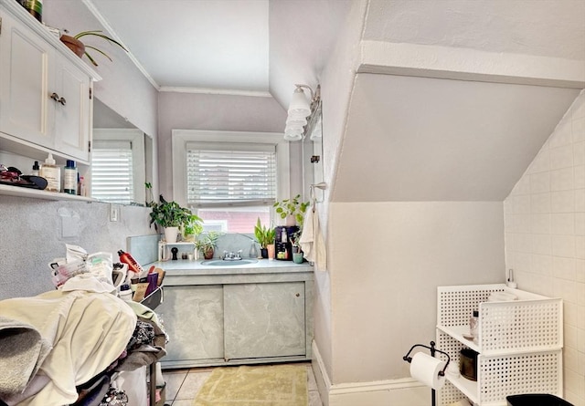 interior space with crown molding, tile patterned floors, lofted ceiling, and sink