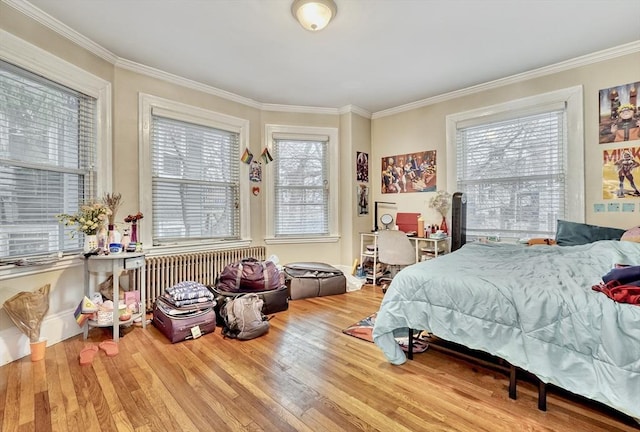 bedroom featuring crown molding, hardwood / wood-style floors, and multiple windows