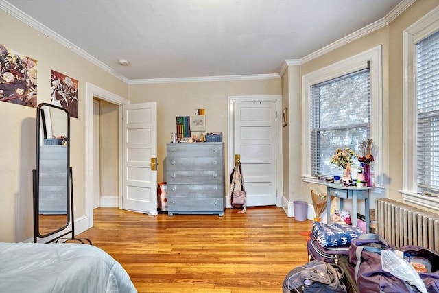 bedroom featuring crown molding, radiator heating unit, and light hardwood / wood-style floors