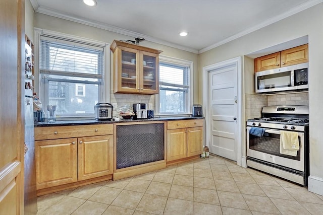 kitchen featuring light tile patterned flooring, dark stone counters, ornamental molding, stainless steel appliances, and backsplash