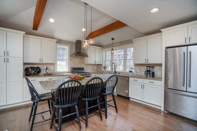 kitchen featuring white cabinets, lofted ceiling with beams, stainless steel appliances, and wall chimney exhaust hood