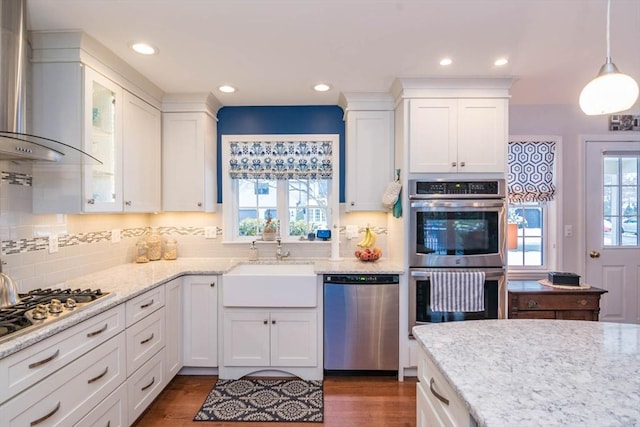 kitchen featuring appliances with stainless steel finishes, wall chimney range hood, and white cabinets