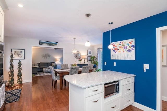 kitchen featuring white cabinetry, light stone countertops, dark wood-type flooring, and pendant lighting