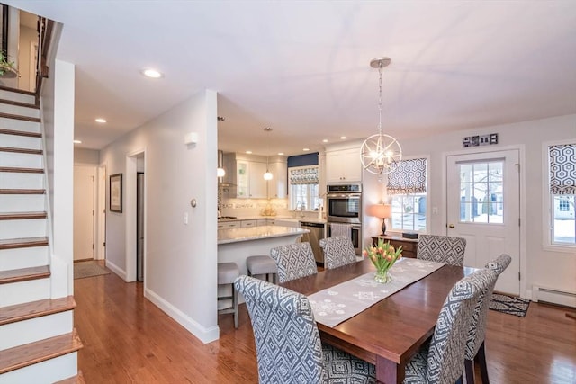 dining room with baseboard heating, a chandelier, and light hardwood / wood-style flooring