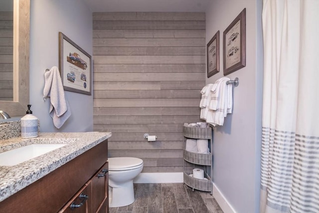 bathroom featuring vanity, wood-type flooring, toilet, and wood walls