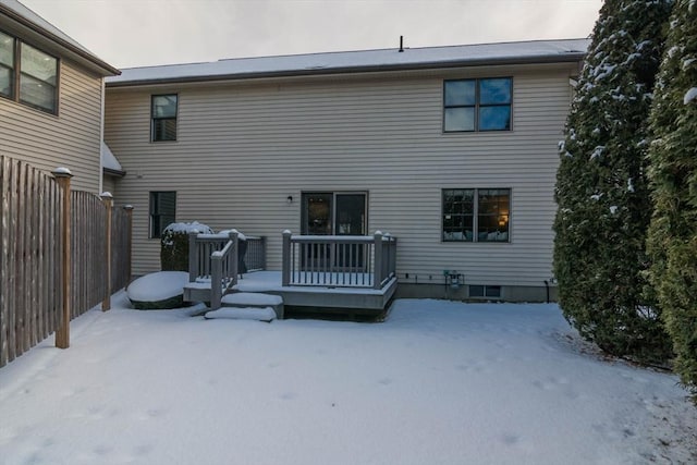 snow covered rear of property with a deck