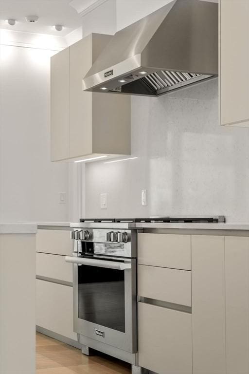 kitchen featuring light countertops, white cabinetry, wall chimney range hood, modern cabinets, and oven