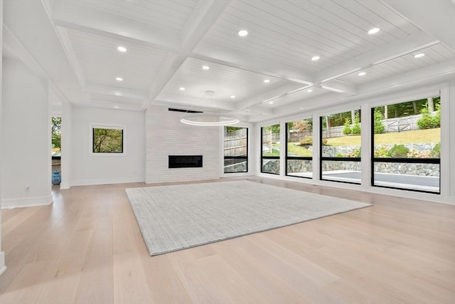 unfurnished living room with a wealth of natural light, light wood-type flooring, beam ceiling, and coffered ceiling