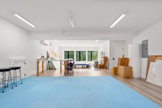 interior space with an AC wall unit, electric panel, and wood finished floors