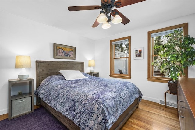 bedroom featuring a ceiling fan, wood finished floors, visible vents, and baseboards