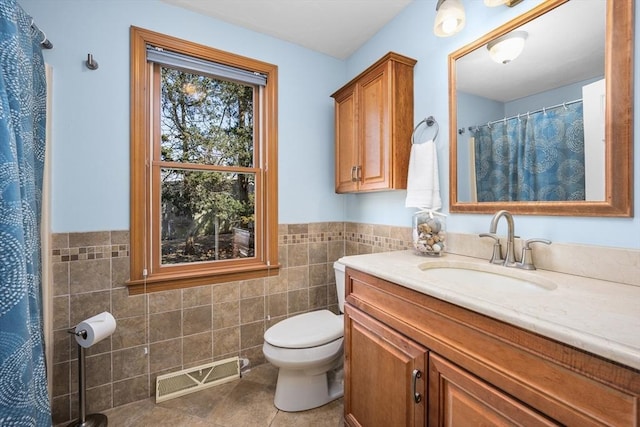 full bath with visible vents, toilet, tile walls, wainscoting, and vanity