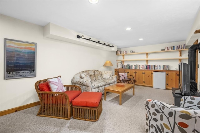 living area with recessed lighting, baseboards, light colored carpet, and a wood stove