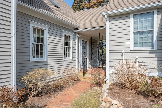 entrance to property featuring roof with shingles