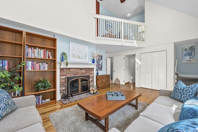 living room with vaulted ceiling, a brick fireplace, wood finished floors, and ceiling fan