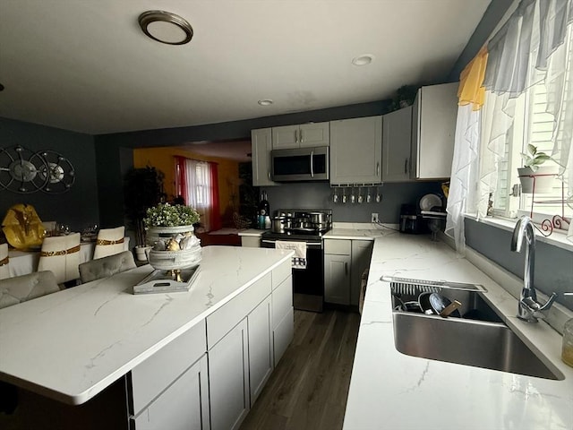 kitchen featuring a kitchen island, light stone countertops, black range with electric stovetop, a sink, and stainless steel microwave