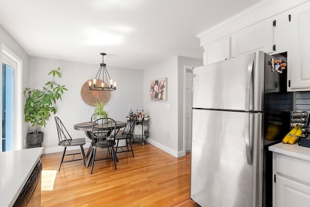128 Parker St Unit 4C, Acton, MA 01720 - kitchen featuring freestanding refrigerator, light wood finished floors, baseboards, white cabinetry, and a chandelier