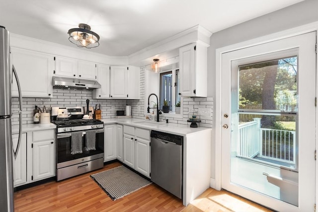 128 Parker St Unit 4C, Acton, MA 01720 - kitchen featuring stainless steel appliances, under cabinet range hood, backsplash, white cabinetry, and light countertops