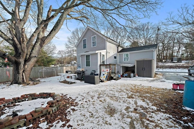 snow covered rear of property featuring a shed