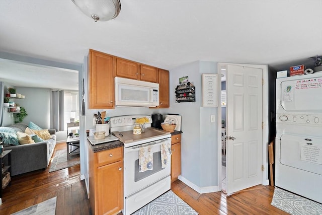 kitchen featuring white appliances, dark wood-type flooring, and stacked washing maching and dryer