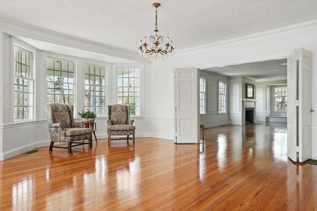 157 Washington St, Duxbury, MA 02332 - sitting room featuring visible vents, an inviting chandelier, light wood-type flooring, crown molding, and a fireplace with flush hearth