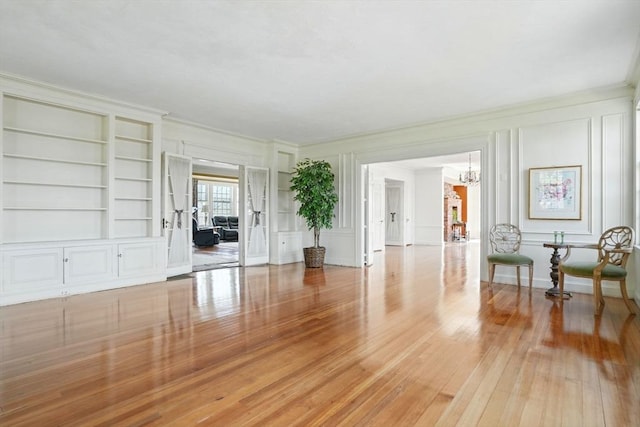 157 Washington St, Duxbury, MA 02332 - interior space featuring a decorative wall, built in shelves, light wood-style floors, and an inviting chandelier
