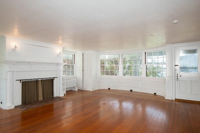40 Prince St, Beverly, MA 01915 - unfurnished living room featuring wood-type flooring, radiator heating unit, a fireplace, and a decorative wall