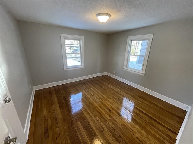 unfurnished room featuring a wealth of natural light, a textured ceiling, and dark hardwood / wood-style flooring