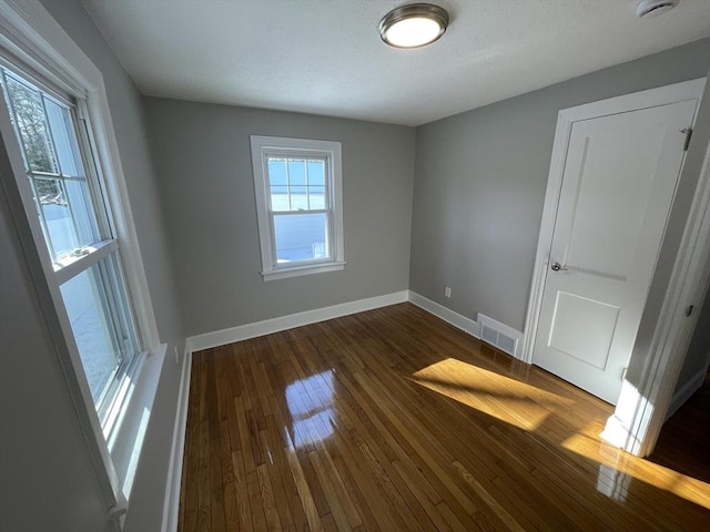 spare room with plenty of natural light and dark wood-type flooring