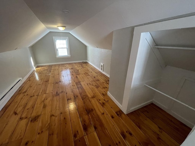 additional living space with hardwood / wood-style flooring, vaulted ceiling, and a baseboard radiator