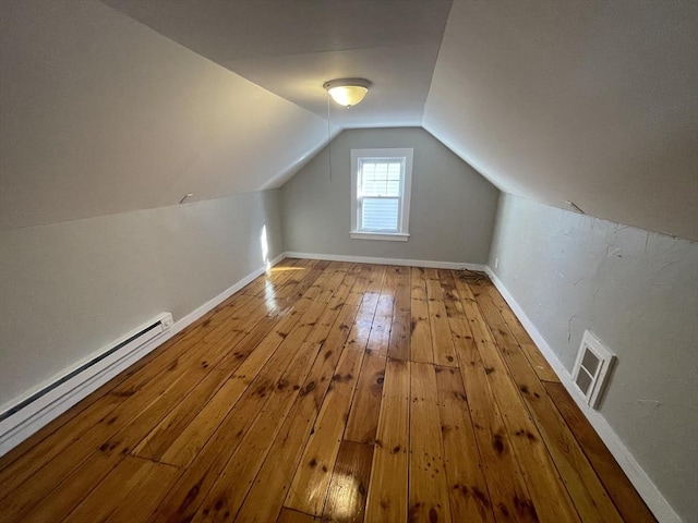 additional living space featuring a baseboard heating unit, vaulted ceiling, and light wood-type flooring