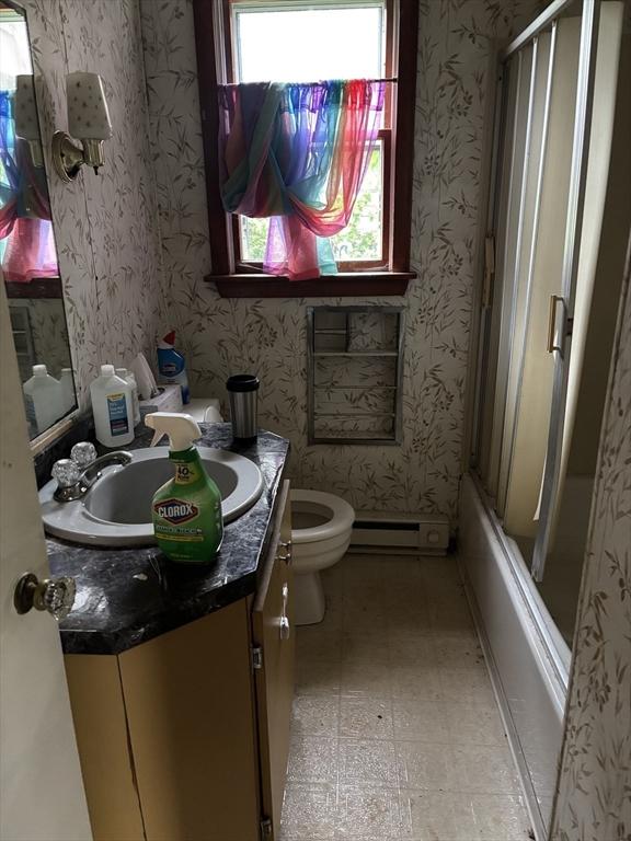 113 Lexington St, Springfield, MA 01107 - full bath with vanity, wallpapered walls, tile patterned floors, a baseboard radiator, and bath / shower combo with glass door