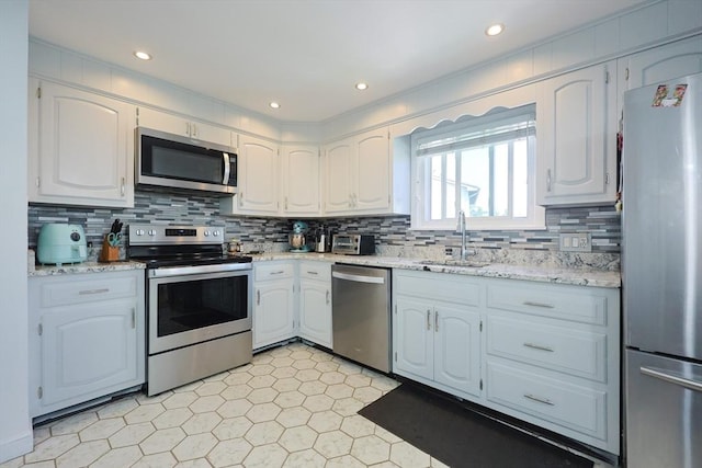 40 Atwood St, Revere, MA 02151 - kitchen with stainless steel appliances, decorative backsplash, white cabinets, light stone counters, and recessed lighting